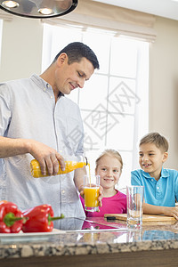 父亲厨房为孩子们供应橙汁图片