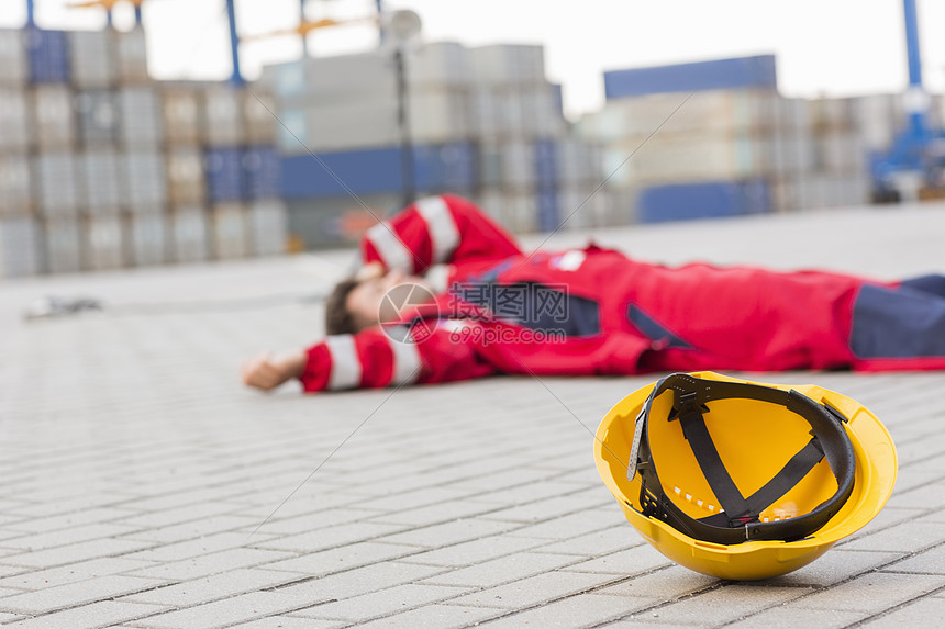 造船厂的黄色硬帽,沮丧的男工人躺造船厂里图片
