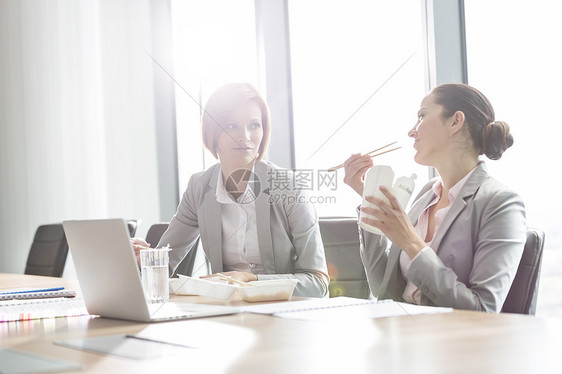 轻的女商人办公室的桌子上吃午饭图片