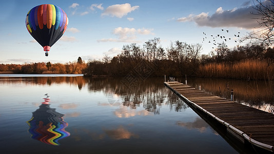 日落时热气球飞过湖景图片