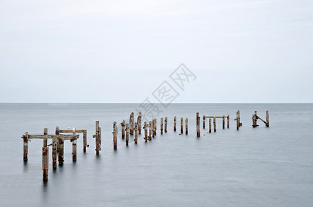 长曝光图像的废弃码头站平静的光滑海洋图片