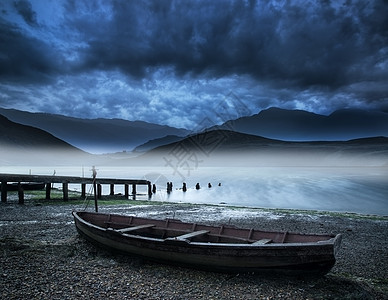 暴风雨的天空景观雾蒙蒙的山湖上,旧船湖岸上图片