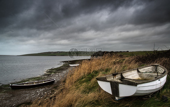 旧的废弃的划船船湖上,头顶上暴风雨的天空图片