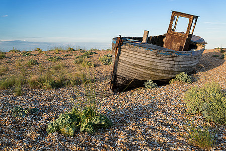日落时Shingle海滩景观上废弃的渔船图片