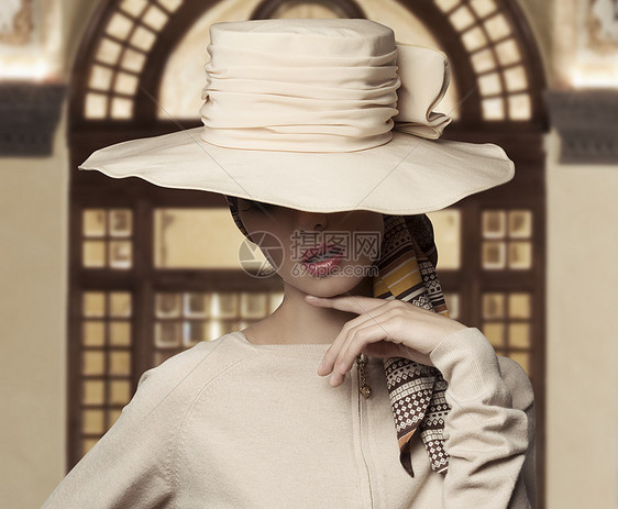 可爱的时尚镜头优雅的女人,脸上盖着大帽子,穿着米色连衣裙图片