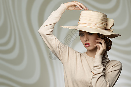 可爱优雅的时尚女孩戴着协调的米色帽子连衣裙,时尚的姿势与浪漫的表情背景图片