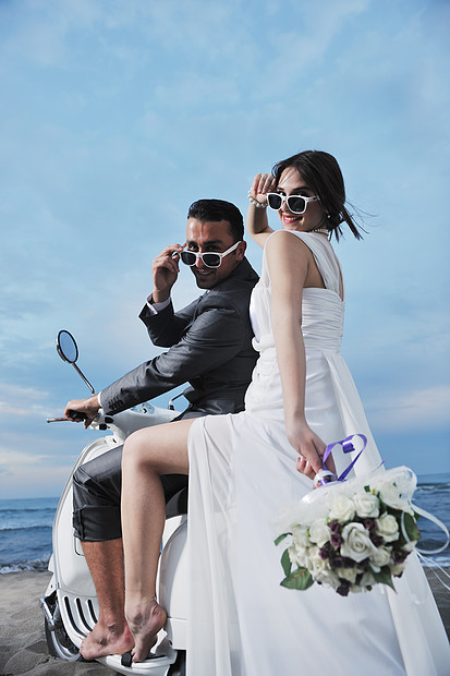 新娘新郎的婚礼Sce刚刚海滩上结婚,骑着白色的滑板车,玩得开心图片