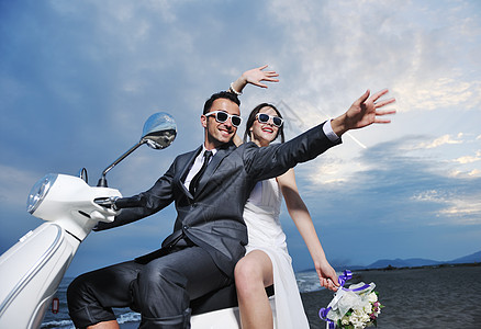 新娘新郎的婚礼Sce刚刚海滩上结婚,骑着白色的滑板车,玩得开心图片