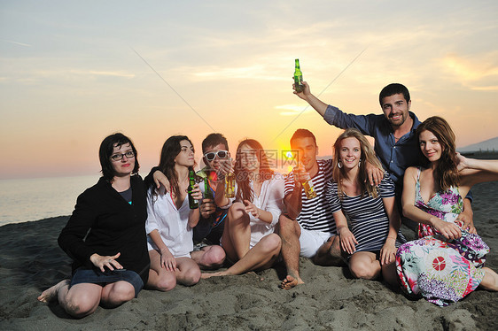 群轻人美丽的日落海滩上享受夏天的聚会图片