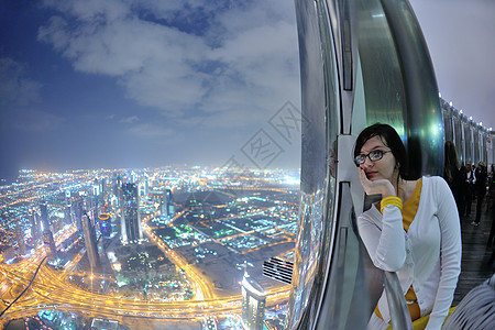 美丽的女人阳台上放松,背景上令人惊叹的夜景图片