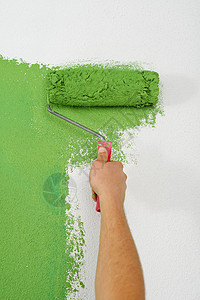 英俊的轻人用蓝色绿色油漆新家的白色墙壁图片