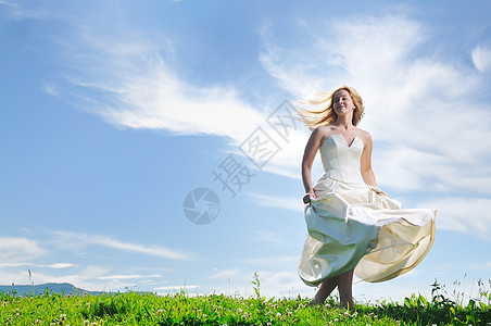婚礼后,快乐的轻美丽的新娘日落的草地上玩得很开心背景图片