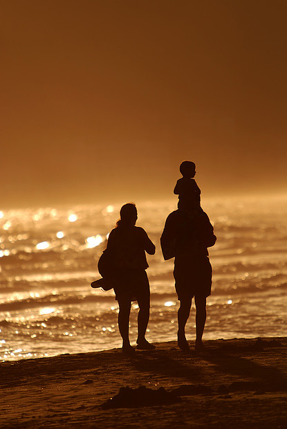 轻的家庭海滩上散步图片