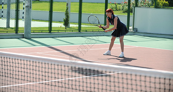 轻健康的女人大早就橙色的网球场上户外打网球高清图片