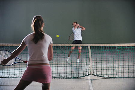 轻女孩网球场里打网球图片
