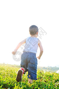 小快乐的孩子玩Windmil玩具,日落时美丽的草地上跑步时玩得很开心图片
