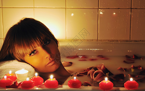 女人美容水疗健康治疗与红花花瓣浴缸图片