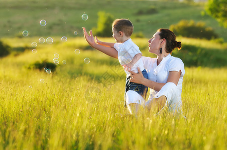 快乐的孩子女人户外玩肥皂泡草地上图片