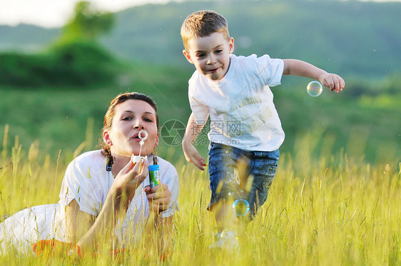 快乐的孩子女人户外玩肥皂泡草地上图片