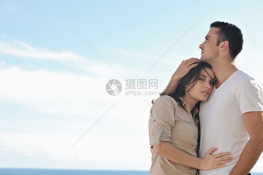 幸福的轻情侣户外阳台上享受浪漫的放松,背景海洋蓝天图片