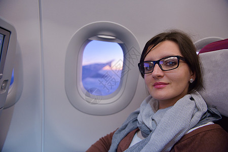 快乐的轻旅游妇女坐飞机上看着温多夫,度假图片