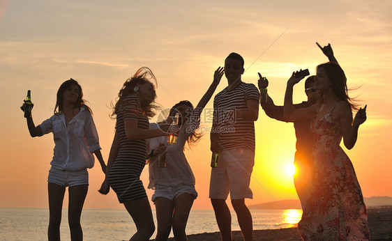 群轻人美丽的日落海滩上享受夏天的聚会图片