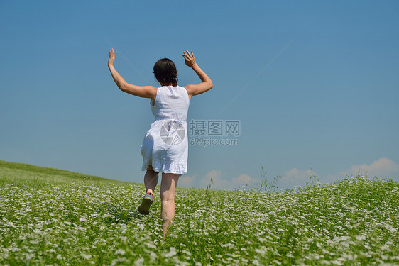 轻快乐的女人绿色的田野,蓝天的背景图片