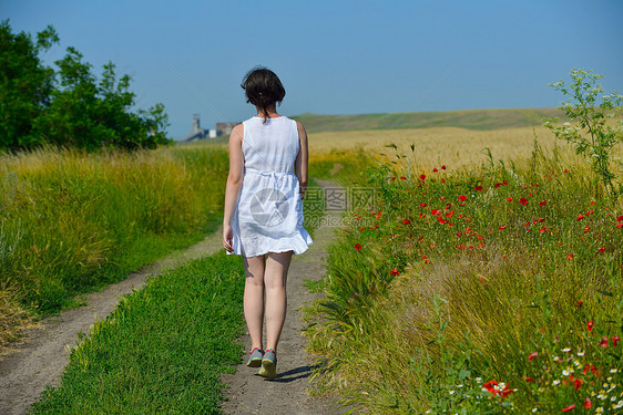轻女子站蓝天的麦田上跳跃奔跑,夏日的背景代表着健康的生活农业理念图片