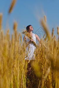 轻的女人站麦田里跳跃奔跑,夏天的背景蓝天,代表着健康的生活农业理念图片