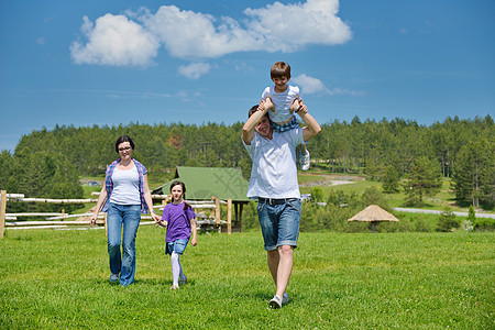 快乐的轻家庭他们的孩子玩得开心,大自然中放松,背景蓝天图片