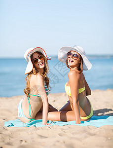 暑假假期女孩们海滩上晒太阳背景图片