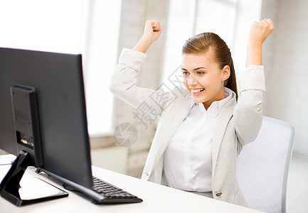 办公室里电脑的快乐女商人的照片背景图片