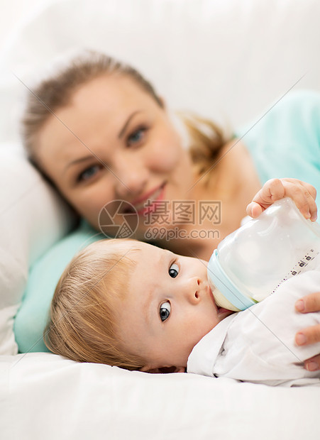 快乐的母亲可爱的婴儿与喂食瓶图片