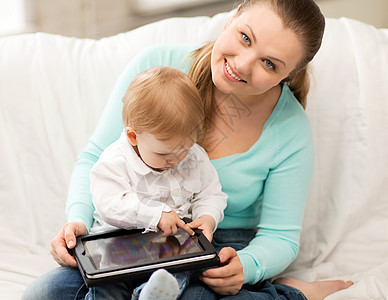 快乐的母亲可爱的婴儿与平板电脑图片