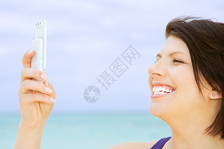 海滩上白色电话的快乐女人图片