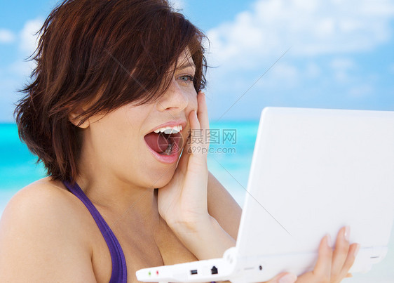 海滩上笔记本电脑的可爱女人图片