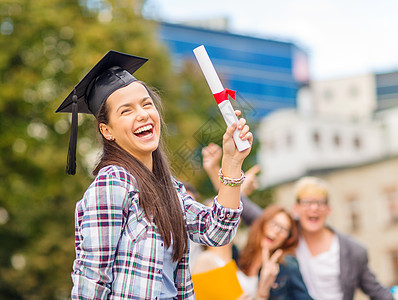 教育,校园青少微笑的十几岁女孩角落帽与文凭同学的背图片