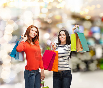 购物,销售,购物中心礼物两个微笑的十几岁女孩购物中心带着购物袋图片