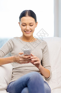家庭,技术,通信互联网女人坐沙发上,家里智能手机图片
