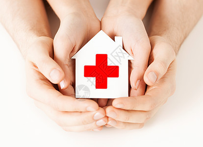 医疗保健医药慈善理念男女手着带红十字标志的白纸屋图片