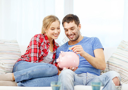 金钱,家庭,金融关系的微笑的夫妇储蓄罐坐沙发上图片