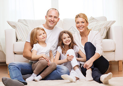 家庭,孩子家庭的微笑的家庭两个小女孩坐家里的地板上图片