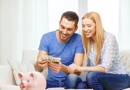 爱家庭金融金钱幸福微笑的夫妇家里用储蓄罐的桌子数钱图片