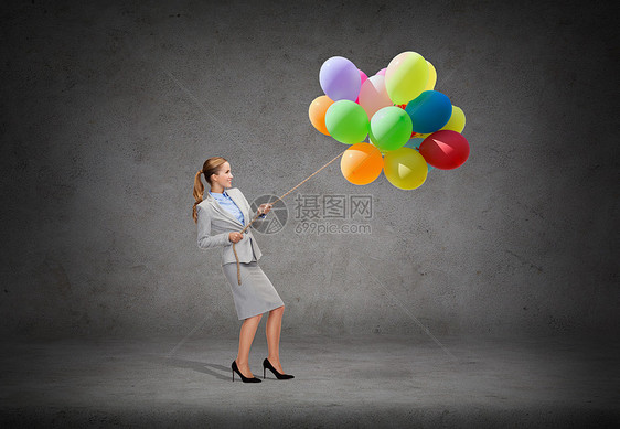 商业教育微笑的女商人用堆气球拉绳图片