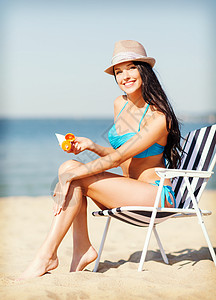 暑假假期女孩海滩椅子上放防晒霜图片