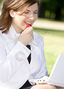 一边吃草莓一边工作的商务女士图片