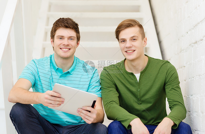 教育技术微笑的男学生与平板电脑坐楼梯上图片