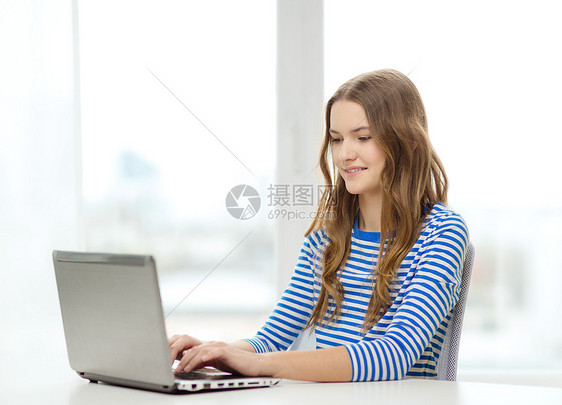 家庭,技术互联网微笑的十几岁女孩带着笔记本电脑图片