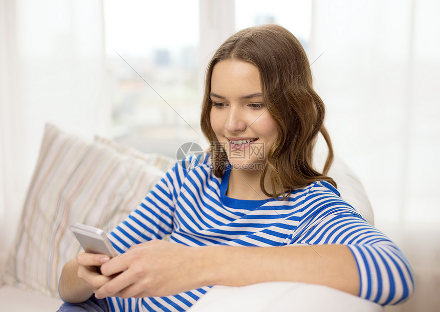 家庭,技术互联网微笑的十几岁女孩,智能手机坐家里的沙发上图片