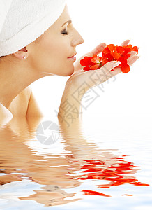 可爱的女人闻着水中的红花花瓣图片